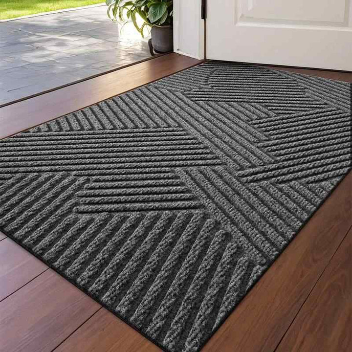 Grey 3D geometric doormat with raised groove pattern placed atthe  indoor entrance on a wooden floor.