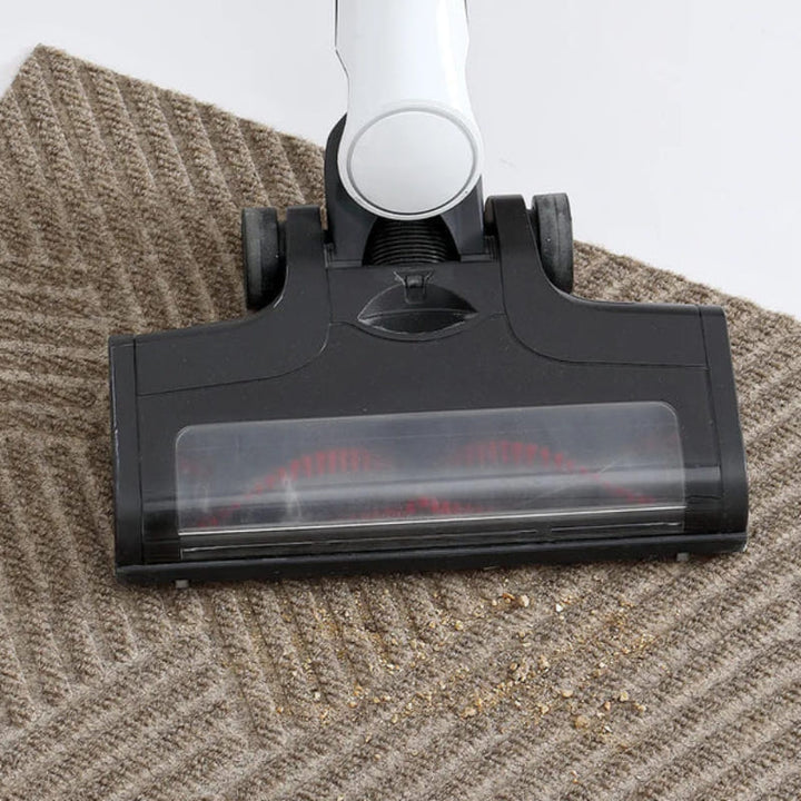 Vacuum cleaner removing dust from beige textured 3D geometric doormat with ribbed surface.