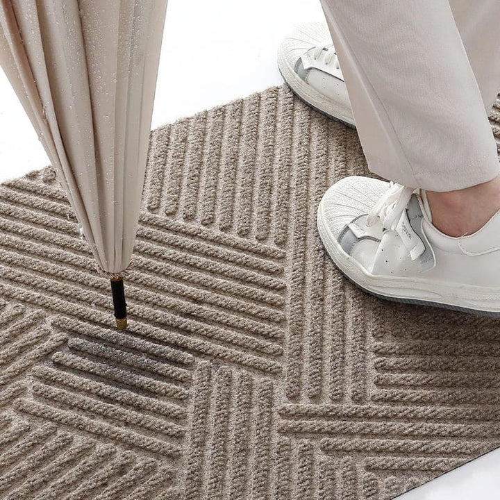 Close-up of shoes and umbrella on beige absorbent doormat showing water and dirt resistance.
