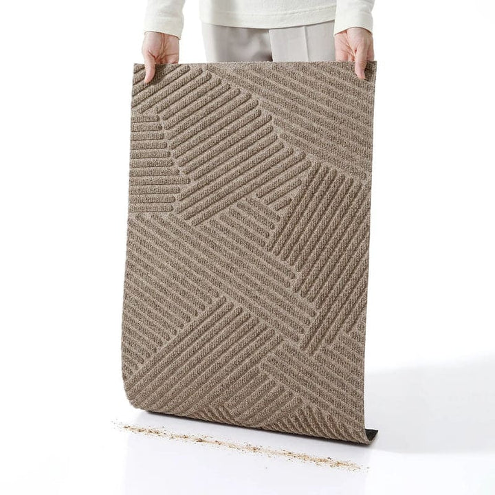 Person holding beige 3D geometric doormat vertically to shake off trapped dust and dirt.