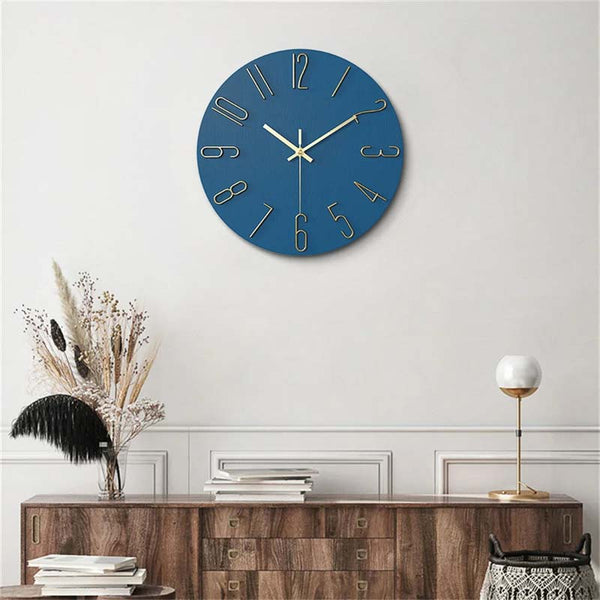 Blue wall clock on a white wall above a wooden console table with decorative items.