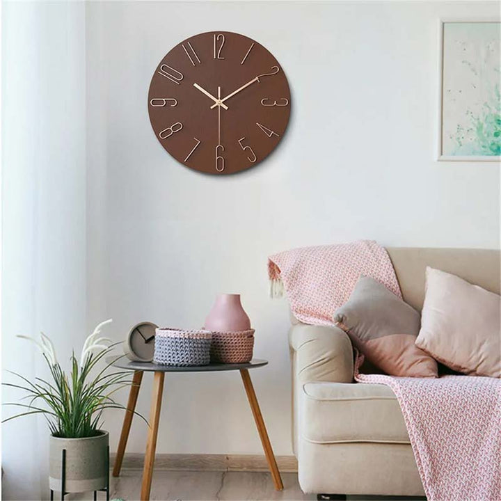 Modern Brown wall clock on a white wall above a beige sofa with pink and gray cushions.