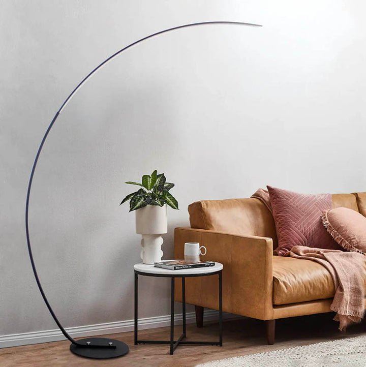 ARC Minimalist Floor Lamp beside tan leather sofa, casting soft light, perfect for reading nooks and Scandinavian lounges.