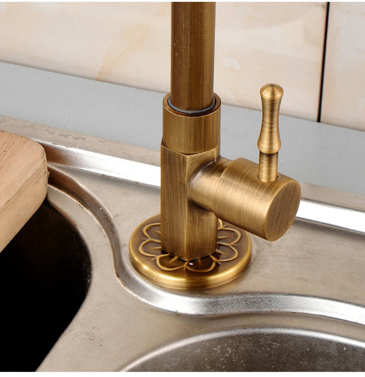 Brass kitchen faucet on a sink with a neutral background