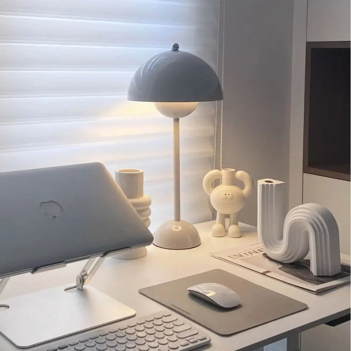 Minimalist cordless white desk setup with a Nordic-style dome table lamp, modern laptop stand, abstract ceramic decor, and soft natural light.