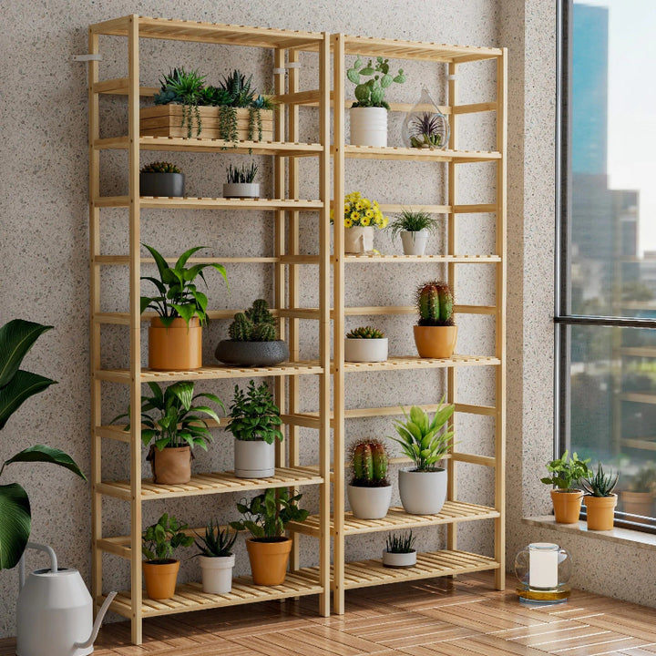 Wooden shelving unit with potted plants in a room with large windows.