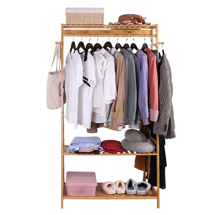 Nordic bamboo garment rack with storage shelves, hanging rail with shirts and jackets, and rattan basket on top, ideal for modern interiors.