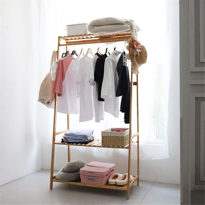 Scandinavian-style bamboo clothes rack with hanging rail and multi-level shelves, styled with white shirts and minimalist bedroom storage.