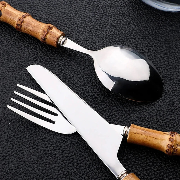 Set of silver cutlery with wooden handles on a textured black surface