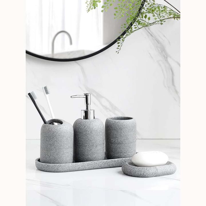 Gray bathroom accessory set with toiletries on a white surface.