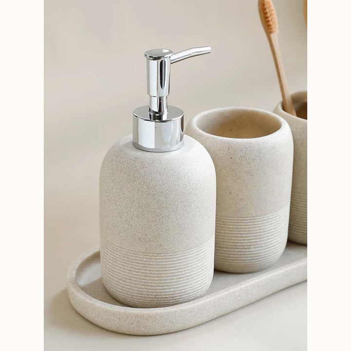 Ceramic soap dispenser with a pump on a tray, surrounded by bathroom items.