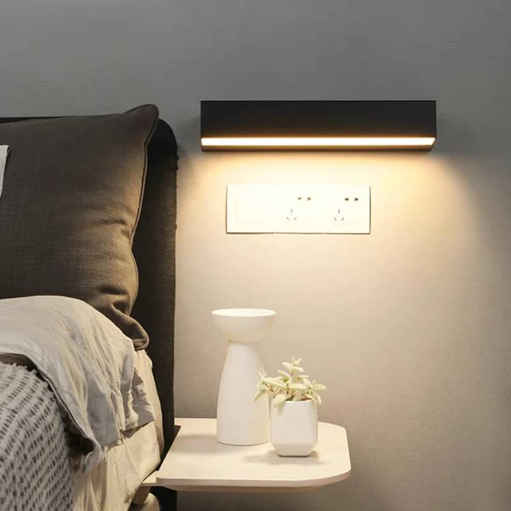 Modern wall light fixture above bedside table, enhancing bedroom decor.