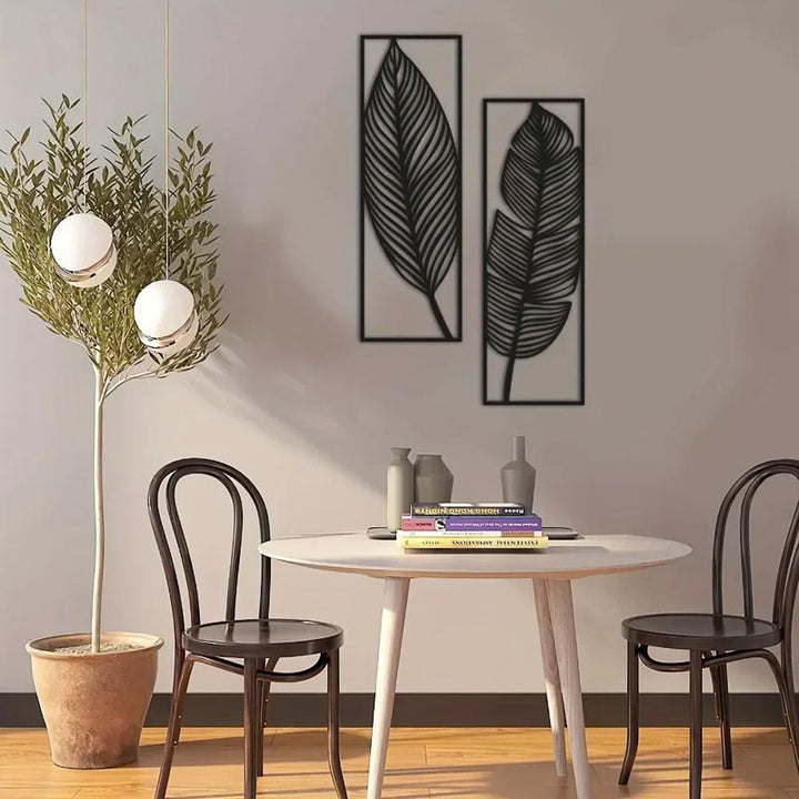 Dining area with a round table, chairs, and wall art of leaves.