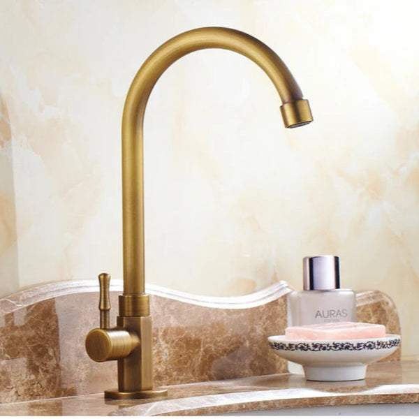 Gold faucet on a marble countertop with a decorative bowl and container.