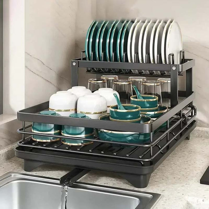 Dish drying rack with green and white dishes on a kitchen counter.
