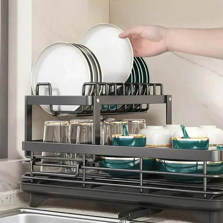 Gray dish rack with plates, glasses, and bowls on a kitchen counter.