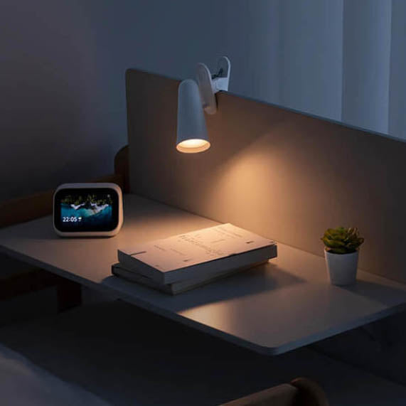 IMIJA lamp clipped onto a wooden headboard, illustrating versatile clip-on feature ideal for bedside reading and minimalist interiors.