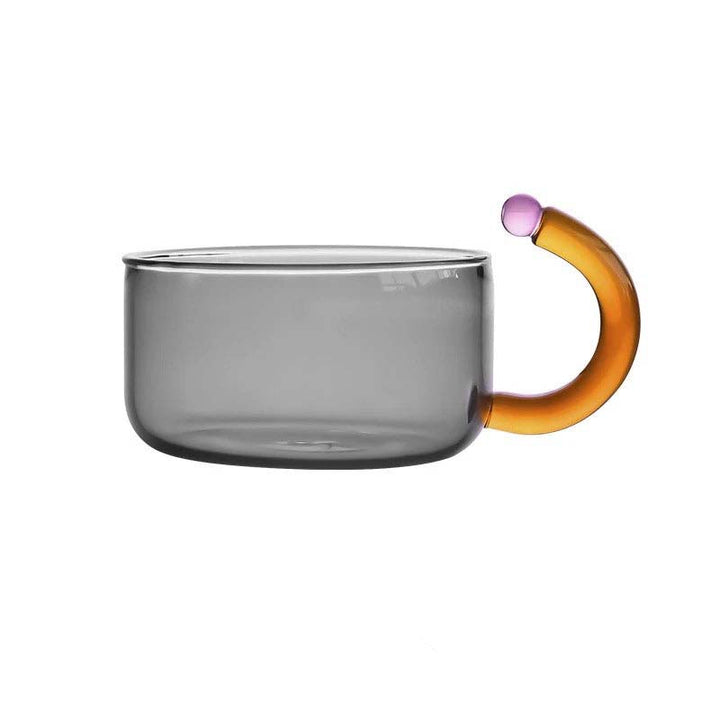 Clear glass mug with a multicolored handle on a white background