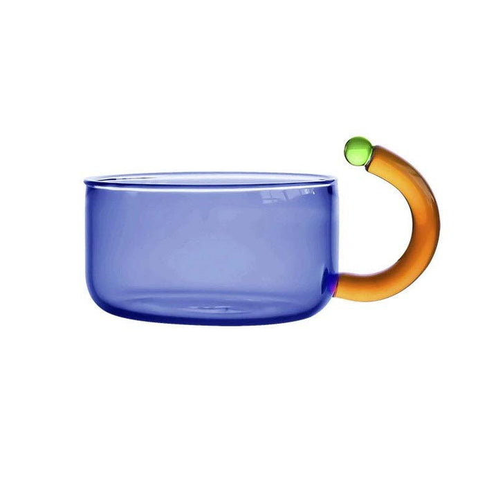 Blue glass mug with an orange handle and green accent on a white background