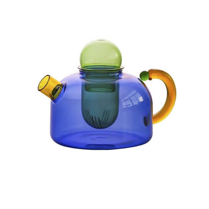 Colorful glass teapot with a blue body, yellow spout and handle, and green lid on a white background.