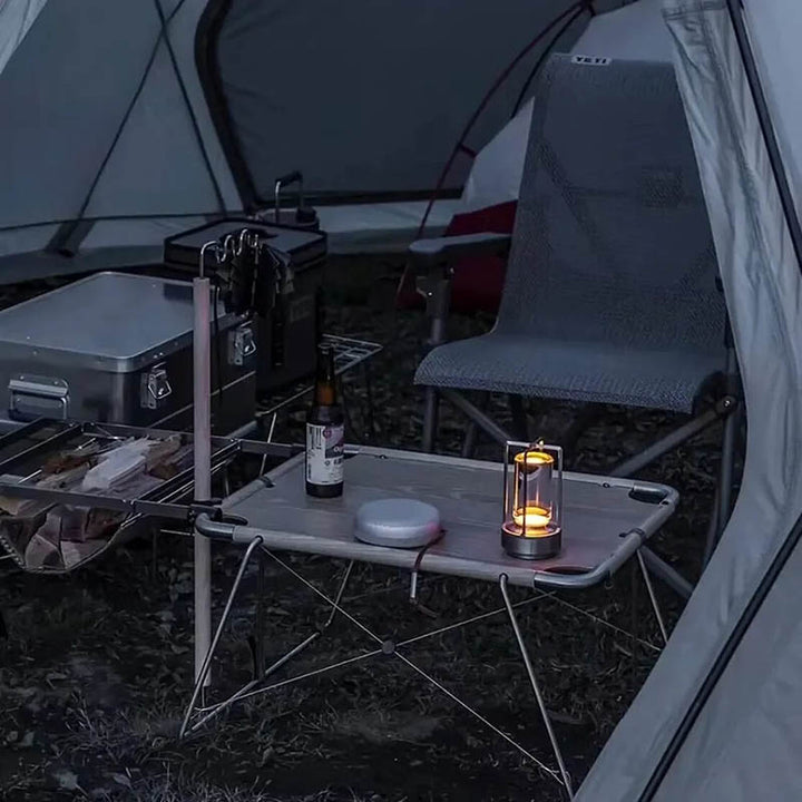 Modern cordless LED lantern illuminating a campsite, ideal for tents, patios, and outdoor dining.
