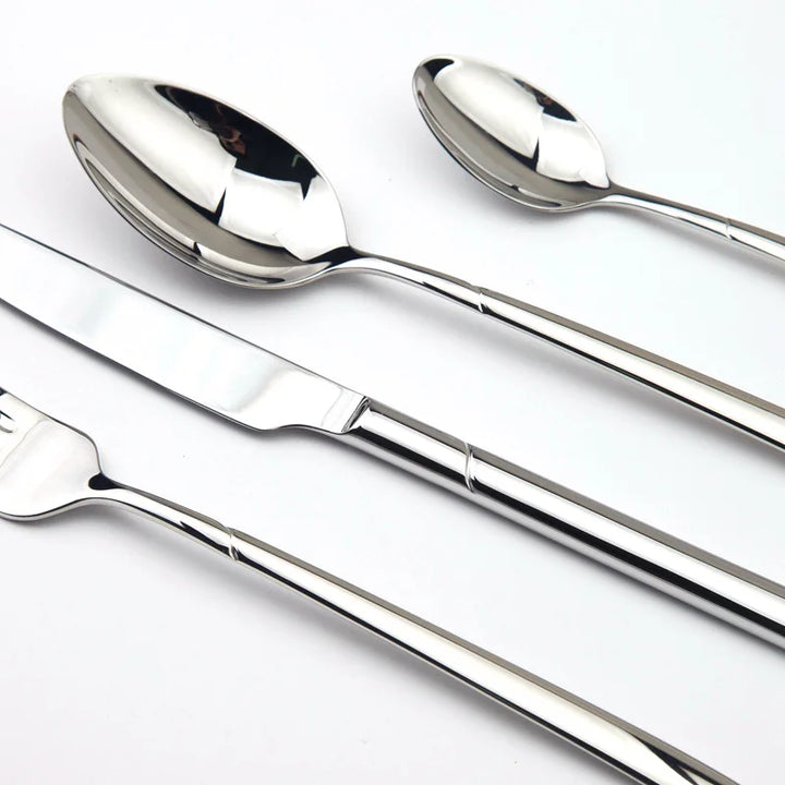 Close up of stainless steel cutlery set including a dinner knife, dinner fork, soup spoon, and teaspoons, displayed on a white background.
