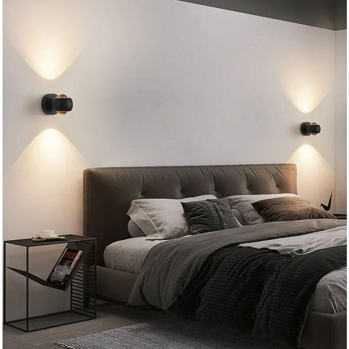 Black adjustable LED wall light mounted in a modern bedroom, casting soft up-and-down lighting for a warm and elegant ambience.