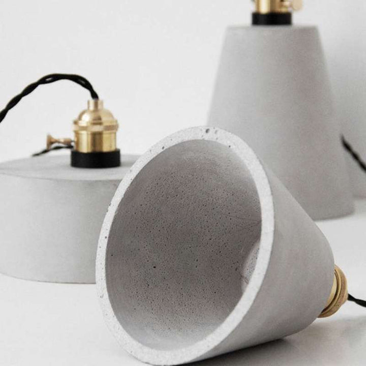 Close-up of concrete pendant lamp showing smooth grey texture and brass socket detail