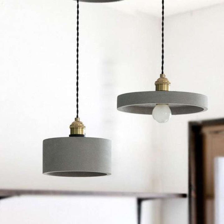 Scandinavian concrete pendant lights with brass fittings hanging in minimalist room