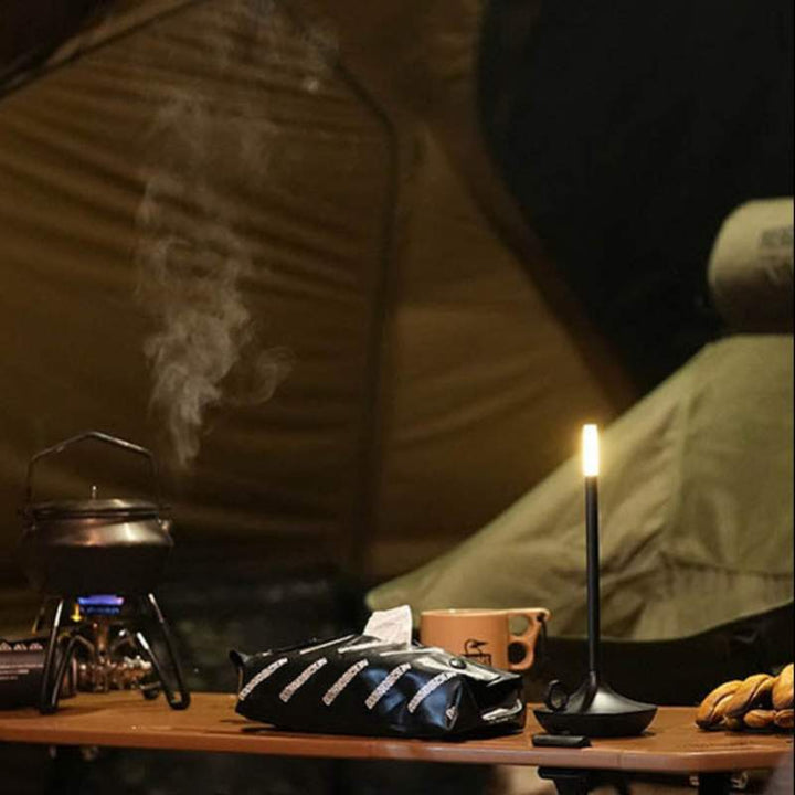 ALLADIN black rechargeable LED lamp on a camping table with cookware – perfect for soft ambient light during outdoor UK adventures.