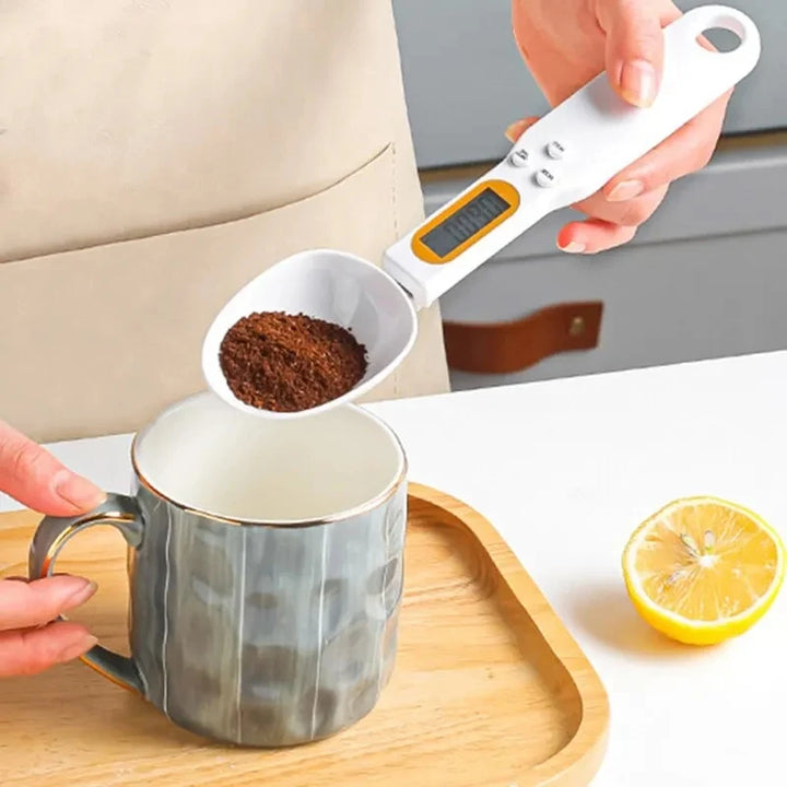 Digital coffee scoop scale measuring ground coffee over ceramic mug on wooden tray