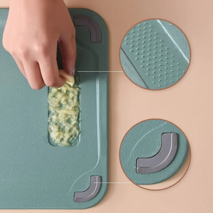 Person using a green kitchenchopping board with a built-in garlic press on a beige surface.