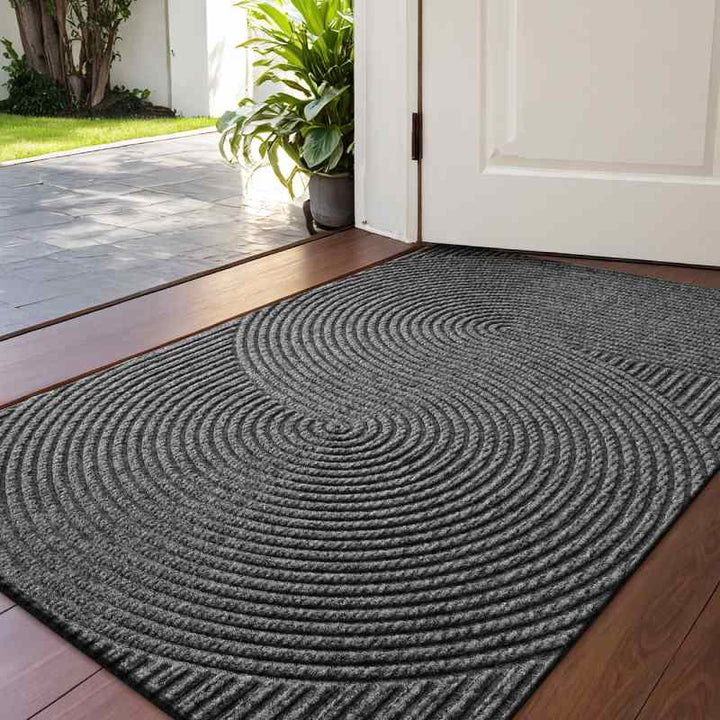 Wide-angle view of dark grey 3D groove doormat at front door, highlighting its modern circular design.