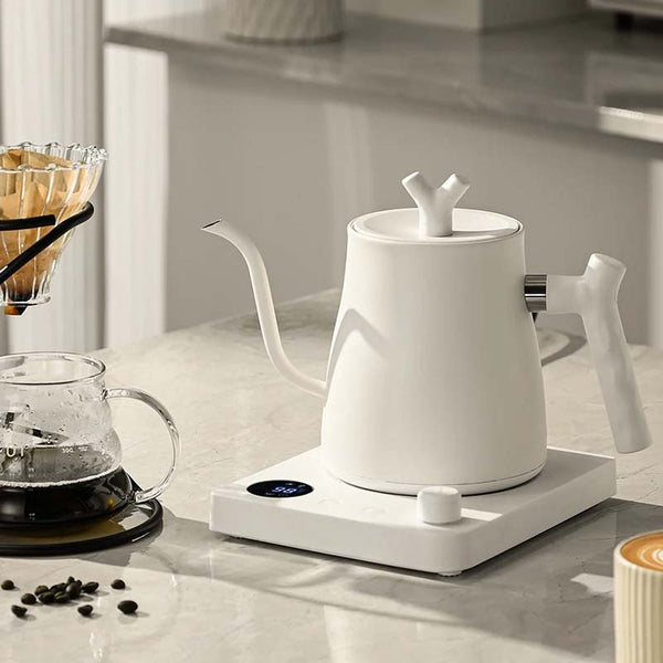White electric kettle on a kitchen counter with coffee-making equipment.
