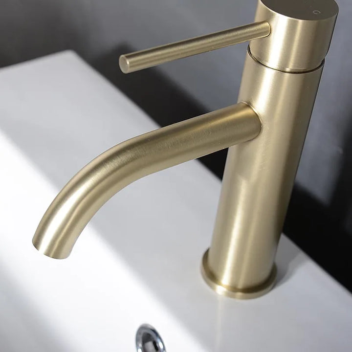 Brushed gold basin mixer tap on white ceramic sink, single lever and modern finish.