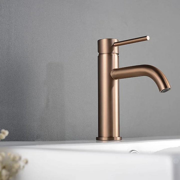 Elegant brushed rose gold bathroom tap on grey wall background, Scandinavian-inspired.