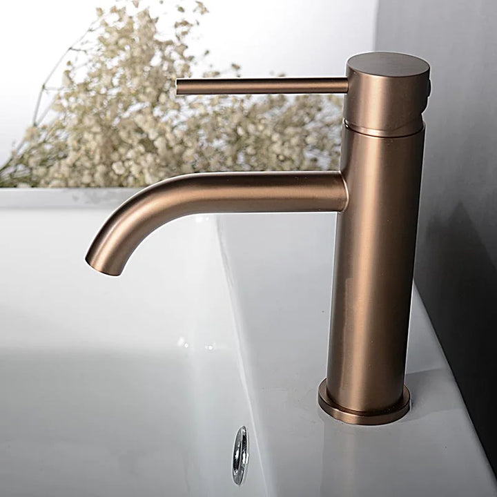 Brushed rose gold basin tap on white sink, curved spout and smooth round body.