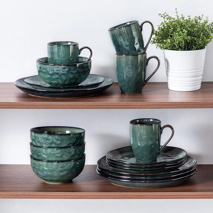 Teal ceramic dinnerware  set on wooden shelves with a plant in the background.