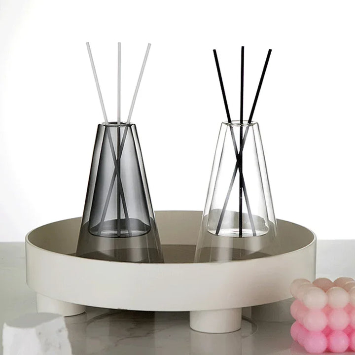 Pair of glass aroma diffusers in clear and grey finish placed on round white tray with candle
