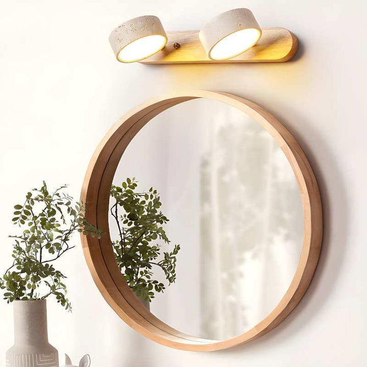 Round mirror with wooden frame and two wall-mounted lights on a white wall.