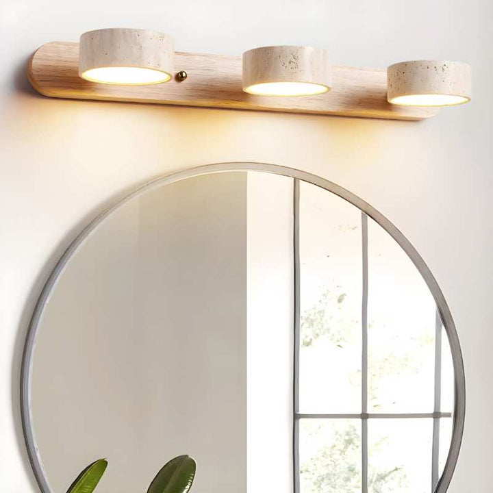 Wooden wall light fixture above a round mirror with a blurred outdoor background