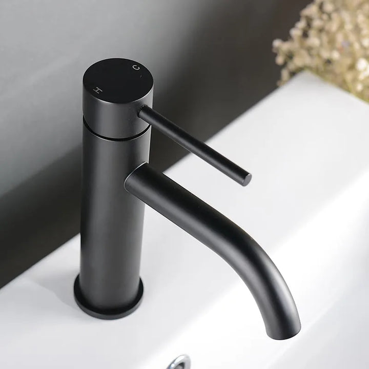 Matte black basin mixer tap with curved spout and single handle, minimalist Nordic style.