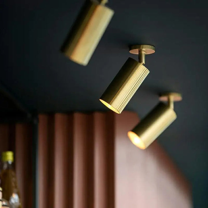 Three gold ceiling lights on a dark ceiling with a blurred background