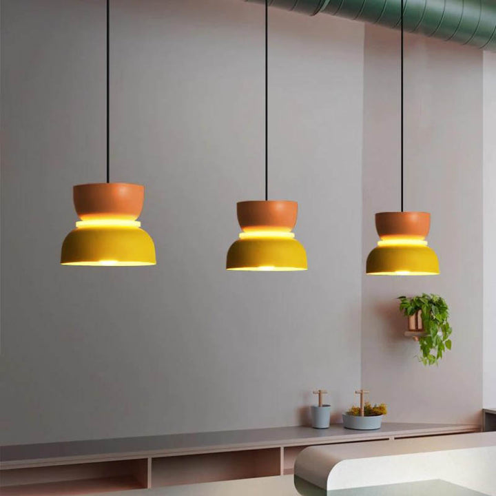 Macaron-inspired pendant lights in yellow and orange with matte finish, suspended over modern  UK kitchen bar.