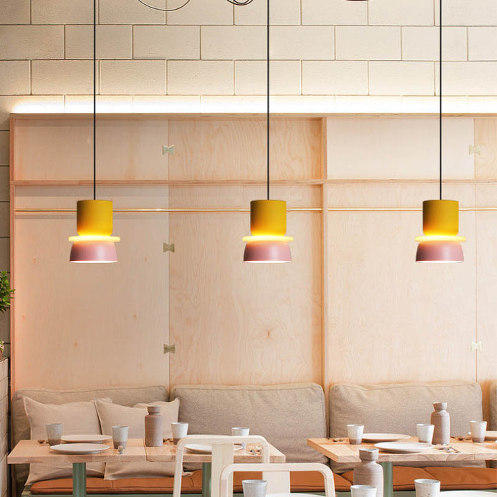 Yellow and pink pendant lights over light wood café seating, ideal for modern Scandinavian restaurants or home interiors.
