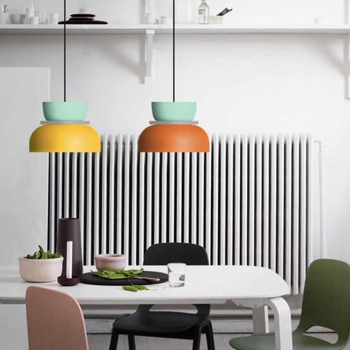 Yellow and orange Scandinavian ceiling lamps over white dining table, ideal for Nordic-inspired kitchens and cafés.