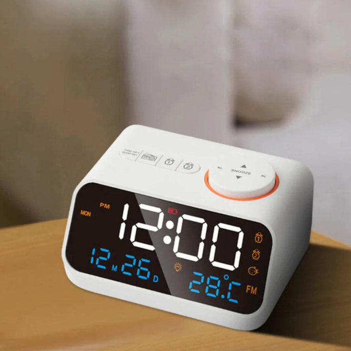White FM Radio LED Alarm Clock on wooden nightstand displaying time, date, and indoor temperature with bright LED screen.