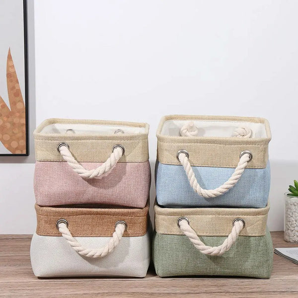 Set of four storage baskets with handles in different colors on a wooden surface.