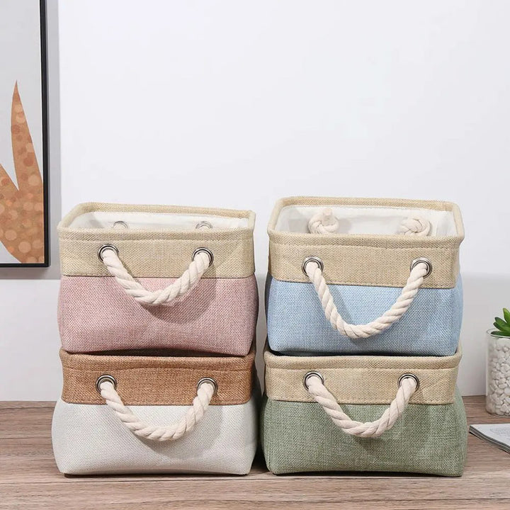 Set of four storage baskets with handles in different colors on a wooden surface.