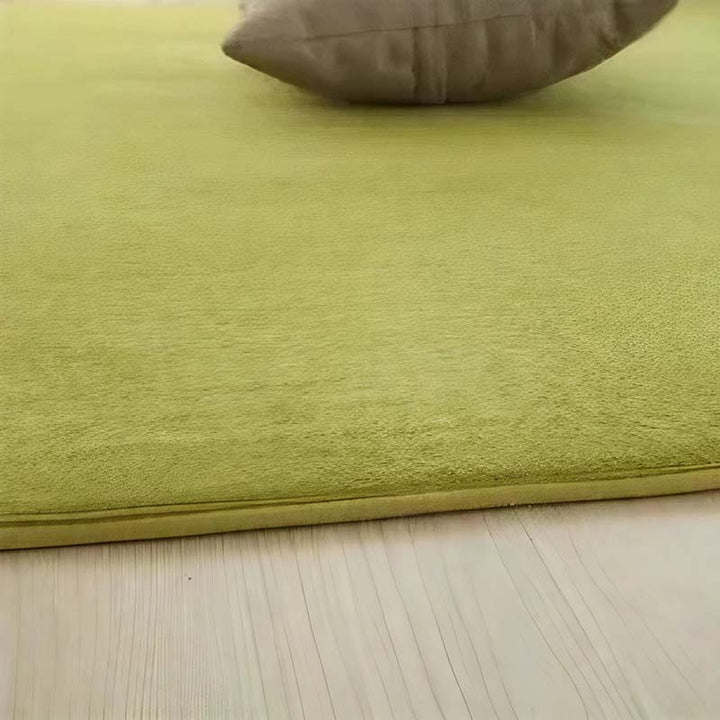 Green rug on a wooden floor with a brown pillow.